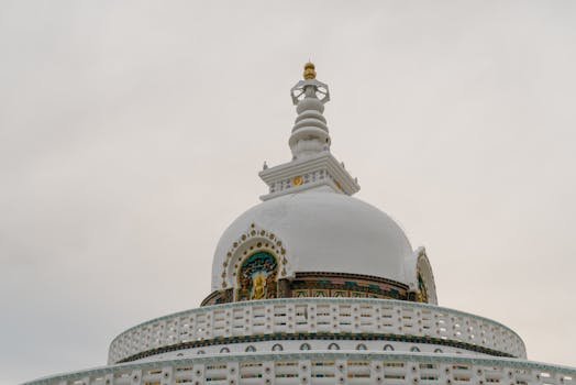 Low angle view of the Shanti Stupa in India with intricate designs against a cloudy sky.