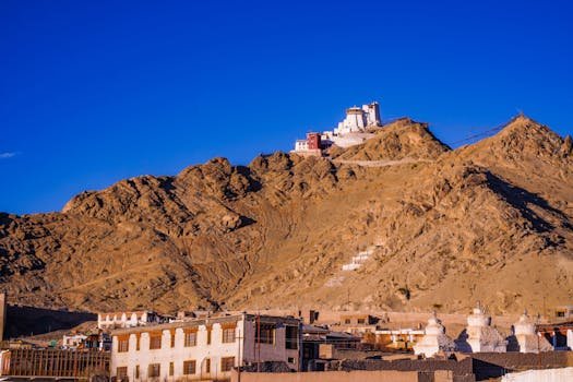 Picturesque view of a monastery atop a hill with clear blue skies in a rugged landscape.